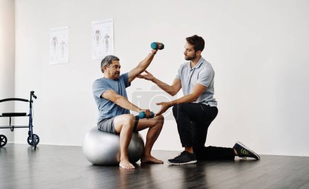 Photo for Slow and easy movements. Full length shot of a young male physiotherapist helping a mature male patient with movement exercises at a clinic - Royalty Free Image