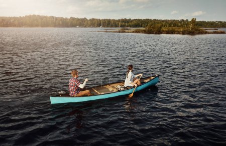Foto de Hacen canoa porque nos encanta. una joven pareja remando un bote en el lago - Imagen libre de derechos
