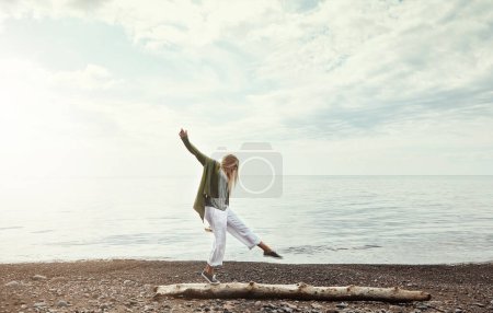 Téléchargez les photos : Ce week-end, passez-le dans la nature. une jeune femme marchant le long d'une bûche au bord d'un lac - en image libre de droit