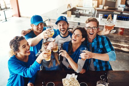 Foto de Empezar el juego con una ronda de cervezas. un grupo de amigos brindando con cervezas mientras ven un partido de deportes en un bar - Imagen libre de derechos
