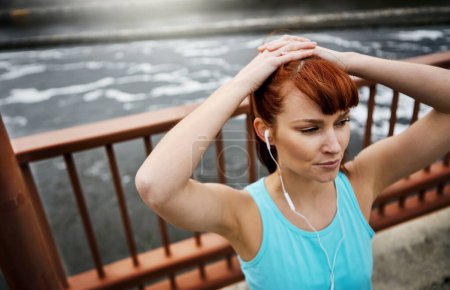 Photo for Music is a powerful motivator for her. a sporty young woman listening to music while out for a run in the city - Royalty Free Image