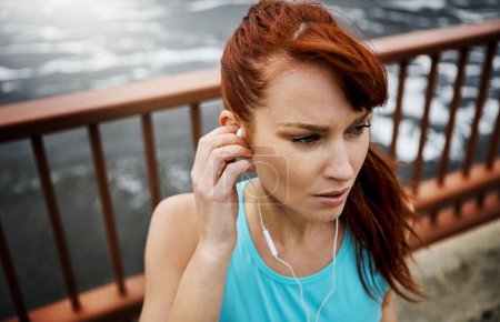 Photo for What better motivator than music. a sporty young woman listening to music while out for a run in the city - Royalty Free Image