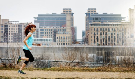 Téléchargez les photos : Courir après ses rêves de forme physique. une jeune femme sportive qui court le long de la ville - en image libre de droit