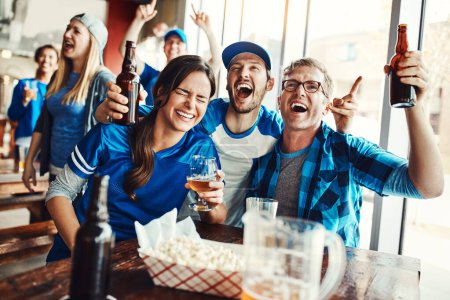 Photo for The bar is where its all going down. a group of friends cheering while watching a sports game at a bar - Royalty Free Image
