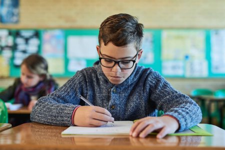 Photo for Working hard to complete his worksheet. an elementary school boy working in class - Royalty Free Image