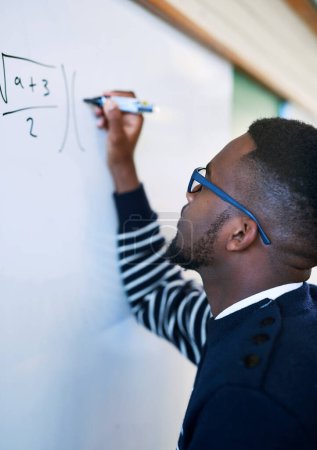 Photo for Theres no problem he cant solve. a young man writing on a whiteboard in a classroom - Royalty Free Image