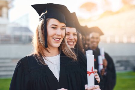 Photo for Each diploma is a lighted match. Portrait of a group of students standing in a line on graduation day - Royalty Free Image