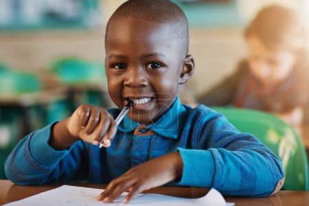 Foto de Todo sonríe cuando hace su trabajo. Retrato recortado de un niño de escuela primaria en el aula - Imagen libre de derechos
