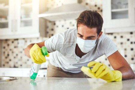 Photo for Leaving no trace of germs. a handsome young man cleaning his kitchen at home - Royalty Free Image