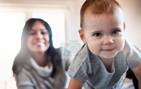 Photo for Outta my way world, I got places to go. an adorable baby girl crawling on a bed with her mother in the background - Royalty Free Image