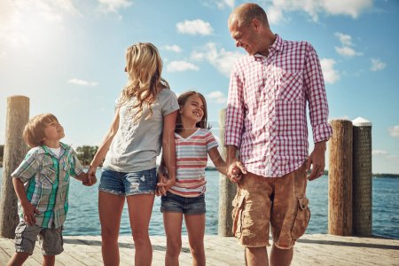 Téléchargez les photos : La famille est amour pur. une jeune famille sur une jetée au bord du lac - en image libre de droit