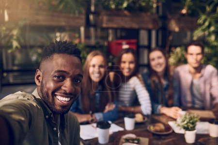 Foto de Buena comida. Mejor compañía. un hombre joven tomando una selfie mientras que fuera con amigos en un café - Imagen libre de derechos