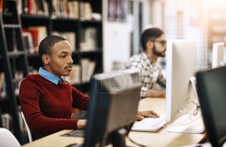 Foto de Internet les ayuda a aprender mucho más. estudiantes universitarios que trabajan en computadoras en la biblioteca del campus - Imagen libre de derechos