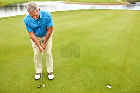 Téléchargez les photos : Déchiquetage et mise sur le terrain. un homme mature jouant au golf dans son temps libre - en image libre de droit
