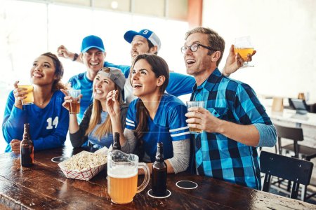Téléchargez les photos : Avec qui mieux vaut regarder le match que les copains. un groupe d'amis buvant des bières en regardant un match de sport dans un bar - en image libre de droit