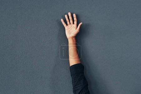 Foto de Escogerme. Estudio de una mujer irreconocible levantando la mano sobre un fondo gris - Imagen libre de derechos