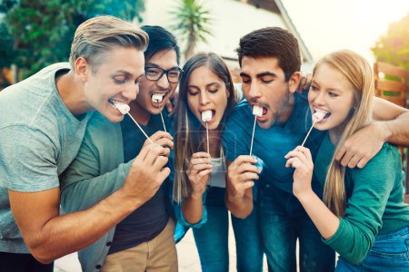 Foto de Es hora de un aperitivo. un grupo de jóvenes amigos posando juntos mientras comen malvaviscos en palos fuera - Imagen libre de derechos