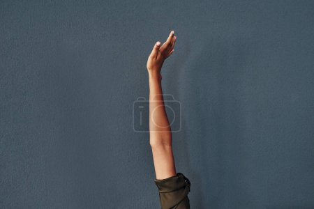 Foto de Alcanza la cima. Estudio de una mujer irreconocible levantando la mano sobre un fondo gris - Imagen libre de derechos