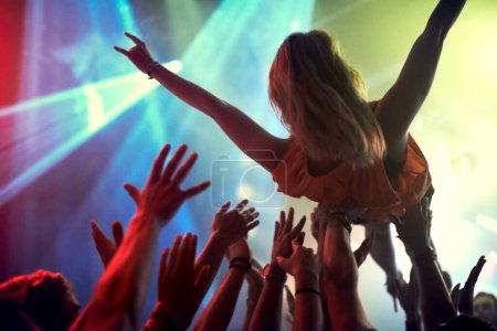 Téléchargez les photos : Concert, festival de musique et une foule de femmes surfant dans un club avec des lumières et des gens en fête. Groupe d'hommes et de femmes ou de fans lors d'un événement rock ou social ou d'un spectacle pour une performance en direct dans une boîte de nuit. - en image libre de droit