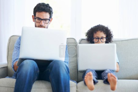 Photo for Father, child and laptop working on sofa in living room together with technology and glasses at home. Dad, kid or little boy pretend to work in remote work on lounge couch with computer indoors. - Royalty Free Image