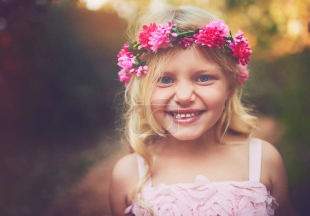 Foto de Soy una princesa de hadas. una niña feliz mirando a la cámara y sonriendo mientras está de pie en medio de un camino de tierra - Imagen libre de derechos
