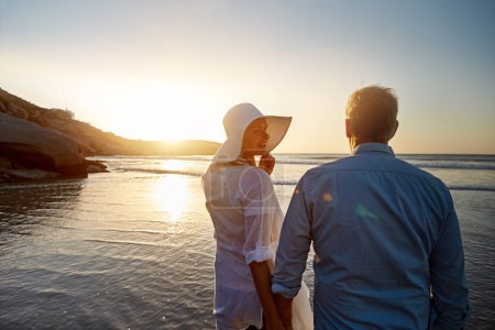 Téléchargez les photos : Les couchers de soleil rendent tout plus romantique. un couple d'âge mûr passe la journée à la plage - en image libre de droit