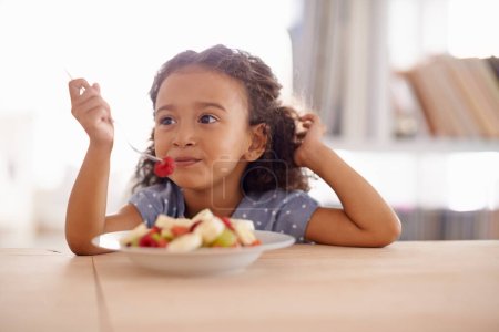 Photo for Eating child, breakfast and fruit salad at home with happiness and wellness meal with a smile. House, nutrition and young girl with healthy food and fruits of a hungry kid in the morning at a table. - Royalty Free Image