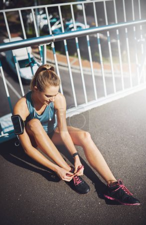 Photo for Making sure shes ready for her run. a sporty young woman tying her laces before a run - Royalty Free Image