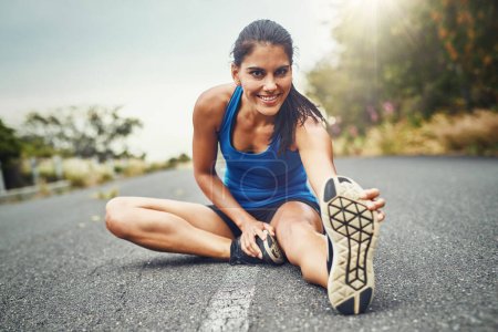 Téléchargez les photos : Étirez-vous avant de courir. une jeune belle femme s'entraîne pour un marathon en plein air - en image libre de droit