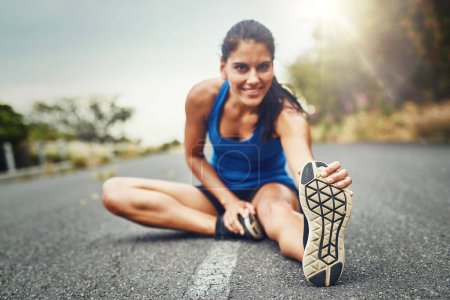Foto de Estirar las piernas es muy importante cuando corres. una joven hermosa mujer entrenando para un maratón al aire libre - Imagen libre de derechos