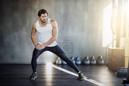 Photo for He never forgets to stretch. a handsome young man warming up before his workout - Royalty Free Image