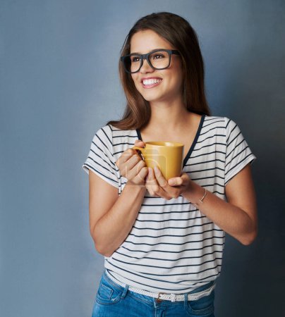 Foto de Su nivel de confianza define el ritmo hacia sus objetivos. Foto de estudio de una joven atractiva sosteniendo una taza de café sobre un fondo gris - Imagen libre de derechos