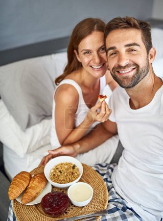 Foto de No es un domingo por la mañana sin desayuno en la cama. una feliz pareja joven disfrutando del desayuno en la cama juntos en casa - Imagen libre de derechos