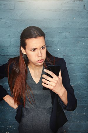 Foto de Ya era hora de una actualización del teléfono. una mujer de negocios enojada mirando su teléfono en exasperación - Imagen libre de derechos