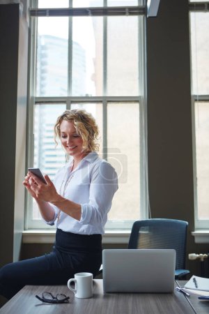 Photo for Keeping track of her work schedule using her phone. a businesswoman using a phone in an office - Royalty Free Image