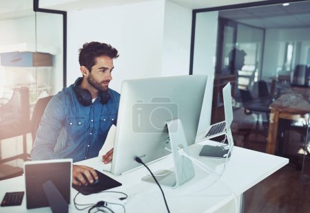 Photo for Focused on the finer details. High angle shot of a handsome young businessman working on his computer in the office - Royalty Free Image