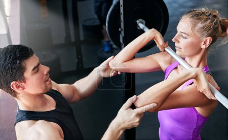 Photo for Working hard to get the results she wants. a young woman lifting weights with her personal trainer assisting her - Royalty Free Image