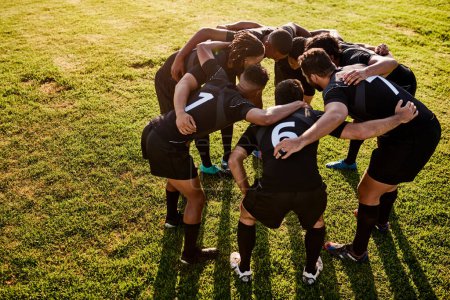 Photo for Building team morale. Full length shot of a diverse group of sportsmen huddled together before playing rugby during the day - Royalty Free Image