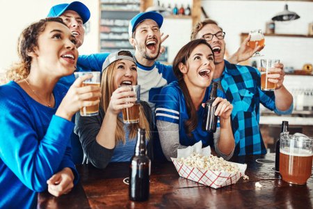 Téléchargez les photos : Leur équipe ne les laisse jamais tomber. un groupe d'amis buvant des bières en regardant un match de sport dans un bar - en image libre de droit