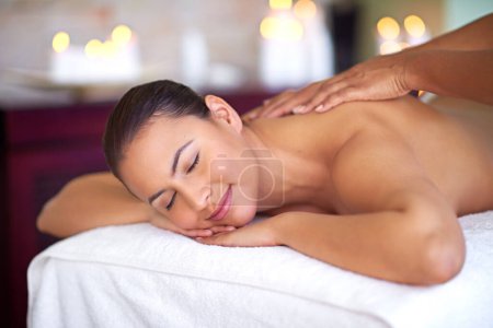 Téléchargez les photos : Paradis trouvé. une jeune femme bénéficiant d'un massage du dos dans un spa - en image libre de droit