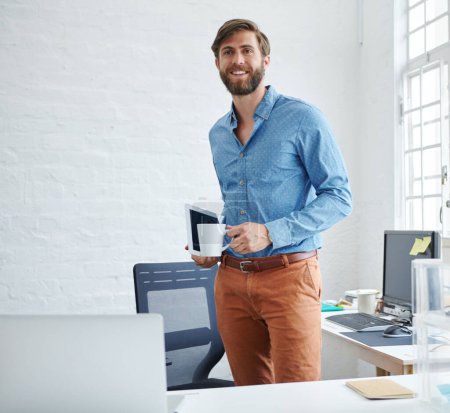 Foto de Está llevando el éxito a otro nivel. un diseñador guapo sosteniendo una taza de café y una tableta digital - Imagen libre de derechos