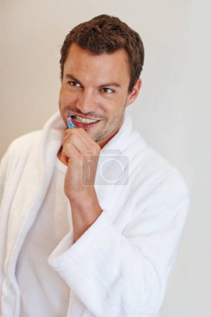Foto de Cuida de esa sonrisa elegante. Un hombre guapo con una bata sonriendo mientras se cepilla los dientes - Imagen libre de derechos