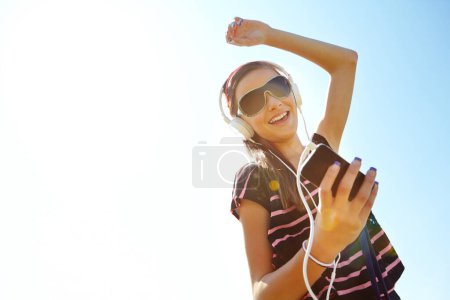 Photo for Let the music move you. A happy young teenage girl dancing outside while listening to music on her headphones - Royalty Free Image