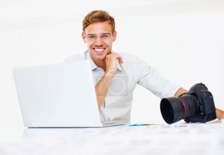 Photo for Photographer smiling. Portrait of young smiling photographer sitting at table using laptop - Royalty Free Image