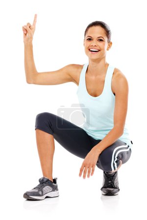 Foto de Apuntando a la cima. Retrato de una atractiva joven en ropa de gimnasia agachada y apuntando hacia arriba - Imagen libre de derechos