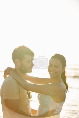 Foto de La vida y el amor se sienten bien. una romántica pareja joven sonriendo con el océano en el fondo - Imagen libre de derechos