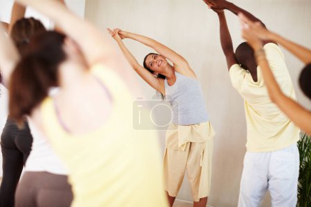 Foto de Estoy sudando. Una bonita instructora de yoga enseñando a su clase cómo realizar una rutina - Imagen libre de derechos