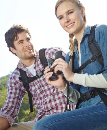 Foto de Deberíamos volver a la pista. Una pareja joven en la cima de una montaña mientras sostiene sus prismáticos - Imagen libre de derechos