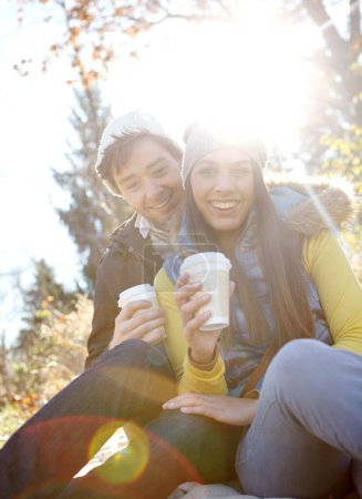 Téléchargez les photos : Romance d'automne. Un jeune couple romantique assis à proximité tout en profitant d'un café en plein air - en image libre de droit