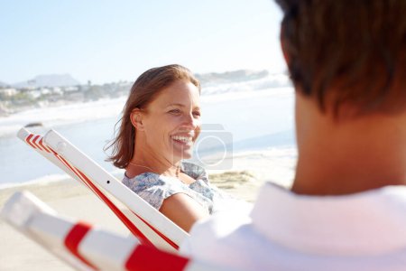 Photo for Sharing a relaxing day on the beach together. A happy couple sitting on deck-chairs on the beach and holding hands - Royalty Free Image